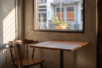 wood table and chair in coffee shop , vintage style with the windows 