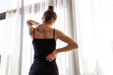 Young woman suffering from neck pain and backache, stretching the muscles at home. back and neck pain woman