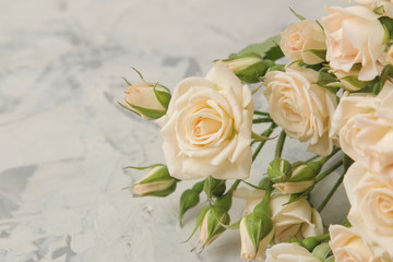 A bouquet of beautiful tender mini roses on a light concrete background. space for text