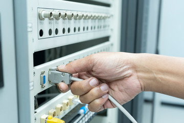 The engineer in a data center of ISP Internet Service Provider Plugging fiber patch cords - Image
