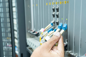 The engineer in a data center of ISP Internet Service Provider Plugging fiber patch cords - Image