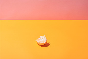 fresh slices of mandarin on yellow surface and pink background