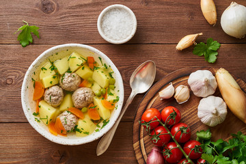 meatballs soup in white plate on old wooden rustic brown table, top view