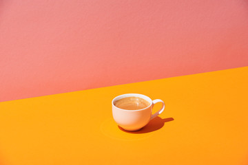 coffee cup on yellow surface and pink background