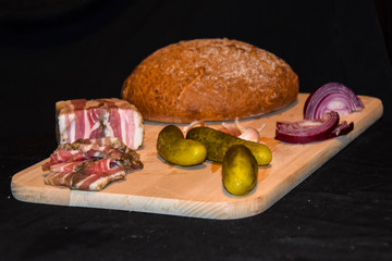 snack for vodka lard onion garlic pickled cucumbers black bread on a wooden board on a black...