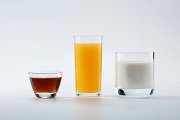 Three glasses of drinks over white background. Milk, orange juice and coffee