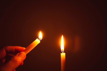 People's hands are lit by candles in the dark. Design for the background, hand with candle, lighting candles.