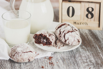 Handmade chocolate cookies, glass and jug with milk, blurred background