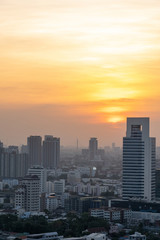 Fototapeta na wymiar Beautiful sunset over modern office building tower in business district downtown center of Bangkok.Cityscape urban of Bangkok city at night in warm light colour tone. Construction business concept.