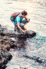 Young wanderer takes pure water from a river