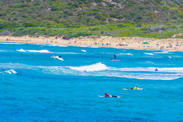 Surfers in Porto Ferro beach on a summer day