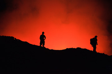 Unrecognized Tourists's silhouettes on Erta Ale Volcano edge illuminated with lava. Danakil Depression, Ethiopia, East Africa