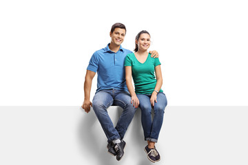 Young casual couple sitting on a panel and smiling at the camera