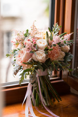 pink and peach wedding bouquet stands on the windowsill
