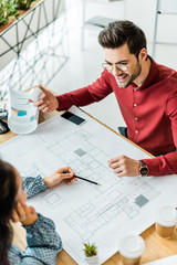 couple of architects sitting at table and working on blueprints in office