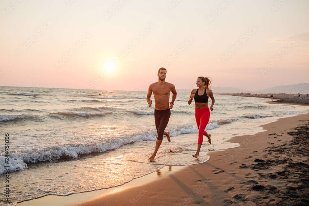 Wall mural Man and Woman Running on Sandy beach