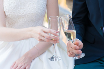 newlyweds are holding champagne glasses and clink glasses