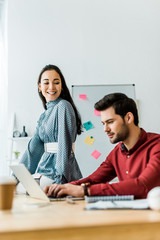 selective focus of multiethnic colleagues working on project and using laptop in office