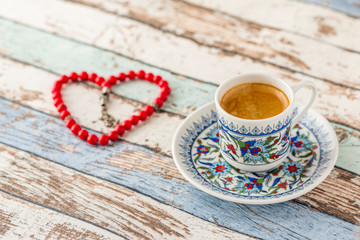 Turkish coffee and heart shaped rosary on turquoise table side view
