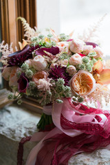 peach dark red wedding bouquet stands on the windowsill