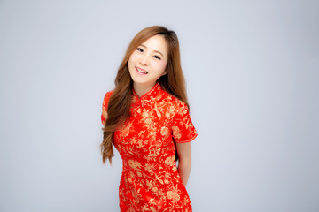 Beautiful portrait happy Chinese New Year young asian woman wear cheongsam smile with gesture congratulation and greeting isolated on white background, festival and celebrate concept.