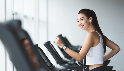 Sportive woman exercising on treadmill in gym