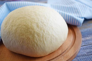 Dough for making delicious cinnamon buns on wooden background.