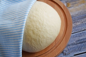 Dough for making delicious cinnamon buns on wooden background.