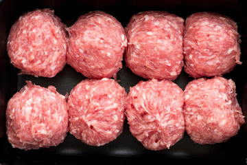 Raw fresh meatballs in black tray, top view