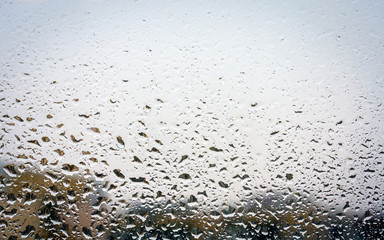 Raindrops on glass, window background view of buildings out of focus.