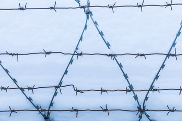 The barbed wire silhouette on the background of snow and blue sky