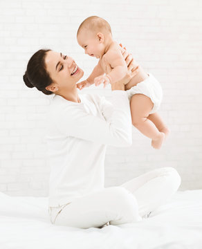 Young mom holding her happy baby in air