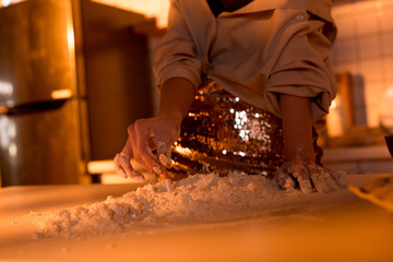 cropped view of woman putting out cigarette in flour while cooking in kitchen with orange light