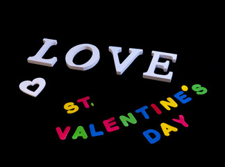 Word love in white and also white heart and colored words valentine's day over black background