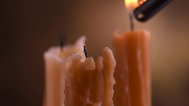 Person lights a candles. Candles flame closeup on a dark background. Three melted wax candles burning at night. Slow motion 4K UHD video footage. 3840X2160