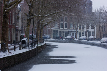 Gouda, South-Holland/The Netherlands - January 22 2019: First real snow in the Netherlands in 2019 a walk through the inner city of Gouda view on the water and street called Hoge Gouwe