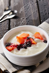 Bowl of fresh mixed berries and yogurt with farm fresh Papaya and blueberry on a wooden table
