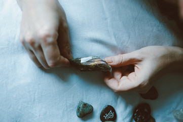 young woman hands showing group of colorful crystal stones during tarot reading with white cloth...