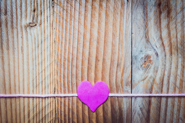 Coeur rose sur un fil, fond en bois