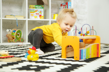 Cute baby girl playing with her toys in the nursery room