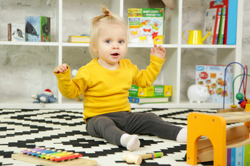 Cute baby girl playing with her toys in the nursery room