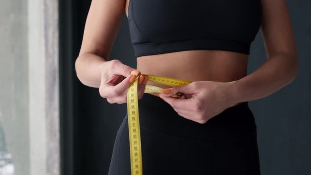 Fitness Woman With Tape Measure Showing Her Waist