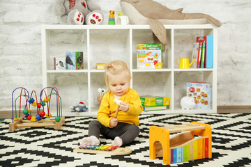 Cute baby girl playing with her toys in the nursery room