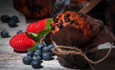 maffin with blueberries and various forest fruits, raspberries, strawberries. There are different types of wood on the table.