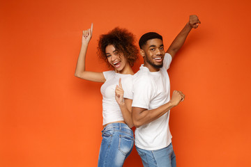 Young lovely african-american couple posing on orange background