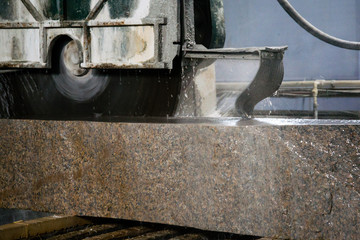 Granite processing in manufacturing. Cutting granite slab with a circular saw. Use of water for cooling. Industrial sawing of granite