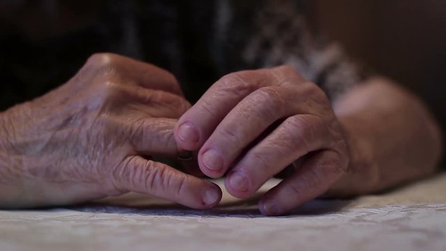 An old woman taking off her wedding ring. The concept of loneliness in old age