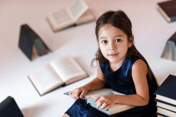 cute little girl is reading a book.