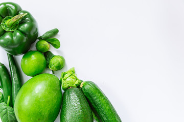 green fruits and vegetables on white background with copy space by diagonal