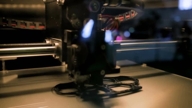 3D printer prints physical 3D model of brass knuckles,with plastic wire filament at modern technology exhibition. Additive technologies, science and futuristic concept